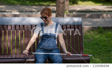 Blind red-haired pregnant woman sitting on a bench outdoors. Blind red-haired pregnant woman sitting on a bench outdoors. 110096896