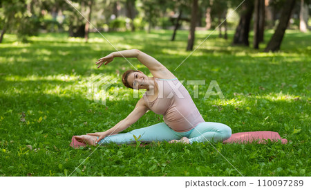 Pregnant caucasian woman doing yoga in the park. Lateral tilt. Pregnant caucasian woman doing yoga in the park. Lateral tilt. 110097289