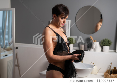 Homosexual preening in front of the mirror. A transgender man combing a wig. 110097337