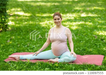 Pregnant caucasian woman doing yoga in the park. Lateral tilt. Pregnant caucasian woman doing yoga in the park. Lateral tilt. 110097555