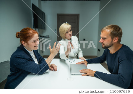 Blond, red-haired woman and bearded man in suits in the office. Business people are swearing during negotiations in the conference room.  110097629