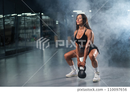 Caucasian woman squats with kettlebell in the gym. Caucasian woman squats with kettlebell in the gym. 110097656