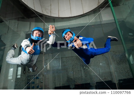 A man and a woman enjoy a joint flight in a wind tunnel and give a thumbs up. Free fall simulator. A man and a woman enjoy a joint flight in a wind tunnel and give a thumbs up. Free fall simulator. 110097766