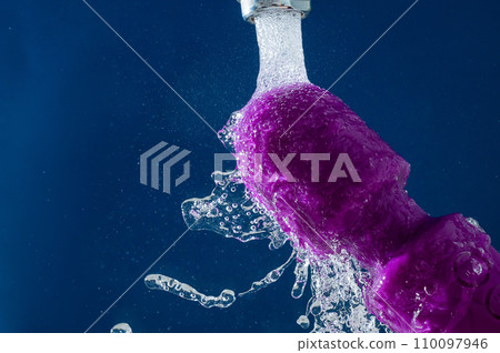 Purple vibrator under running water on a blue background. waterproof sex toy. Purple vibrator under running water on a blue background. waterproof sex toy. 110097946