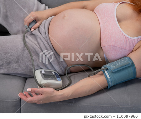 Close-up of the belly of a pregnant woman measuring blood pressure with a tonometer. Hypertension. Close-up of the belly of a pregnant woman measuring blood pressure with a tonometer. Hypertension. 110097960