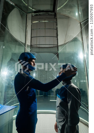 A male instructor teaches a woman how to fly in a wind tunnel. Free fall simulator. 110097993