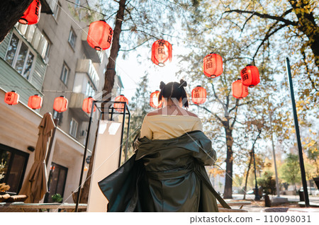 Portrait of an Asian woman against the background of Chinese lanterns outdoors. Portrait of an Asian woman against the background of Chinese lanterns outdoors. 110098031