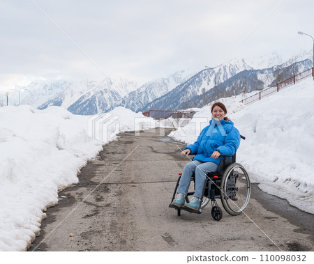 Caucasian woman in a wheelchair travels in the mountains in winter. Caucasian woman in a wheelchair travels in the mountains in winter. 110098032