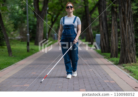 Blind pregnant woman walking in the park with a cane. Blind pregnant woman walking in the park with a cane. 110098052