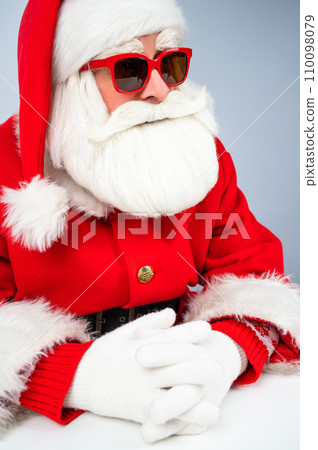 Portrait of santa claus sitting with his arms folded at a white table.  110098079