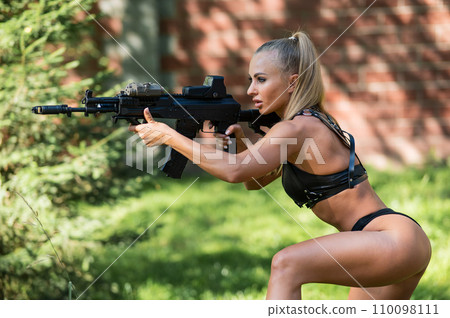 Caucasian woman in bikini with machine gun outdoors. Caucasian woman in bikini with machine gun outdoors. 110098111