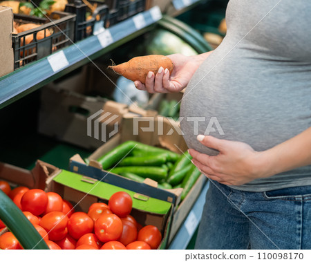 Pregnant woman buying sweet potato in the store. Pregnant woman buying sweet potato in the store. 110098170