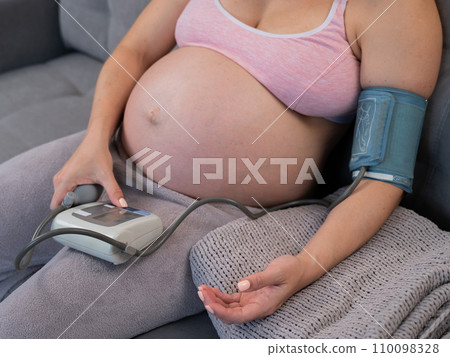 Close-up of the belly of a pregnant woman measuring blood pressure with a tonometer. Hypotension.  110098328