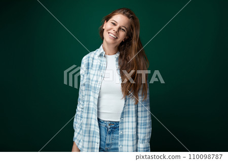 Charming young woman with brown hair wearing a stylish blue checkered shirt on a green background Charming young woman with brown hair wearing a stylish blue checkered shirt on a green background 110098787