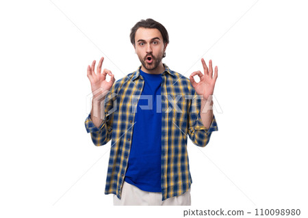 young surprised caucasian brunette man with a beard and an earring is dressed in a blue plaid shirt young surprised caucasian brunette man with a beard and an earring is dressed in a blue plaid shirt 110098980