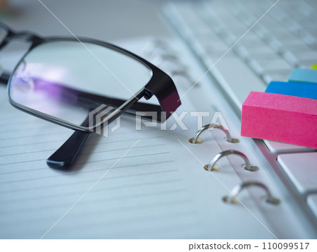 A notebook, glasses, and a keyboard on the table A notebook, glasses, and a keyboard on the table 110099517