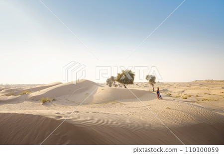 Woman in sands dunes of desert at sunset 110100059