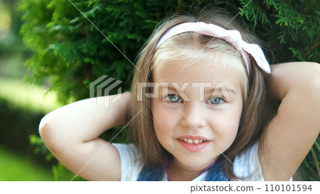Portrait of happy pretty child girl standing in summer park looking in camera. 110101594