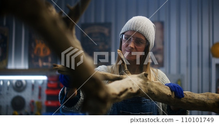 Female artisan grinds tree branch using grinding machine Female artisan grinds tree branch using grinding machine 110101749