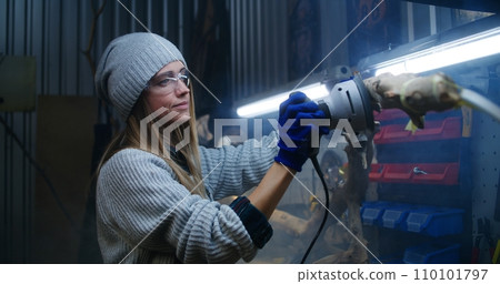 Female carpenter sands tree branch using sanding machine 110101797