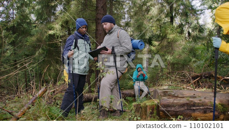 Two multiethnic tourists discuss trail way using tablet computer 110102101