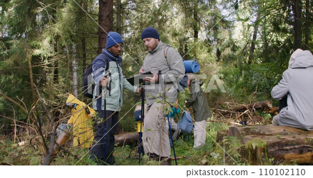 Two multiethnic tourists discuss trail way using tablet computer 110102110