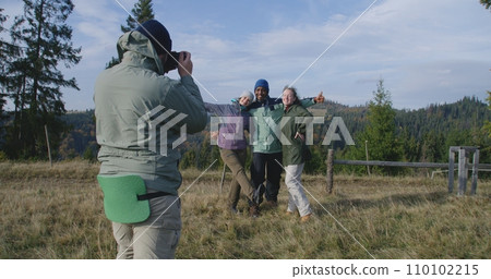 Man takes group picture of multiethnic friends in mountains Man takes group picture of multiethnic friends in mountains 110102215