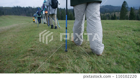 Group of hikers with backpacks walk along trail on mountain hill Group of hikers with backpacks walk along trail on mountain hill 110102220