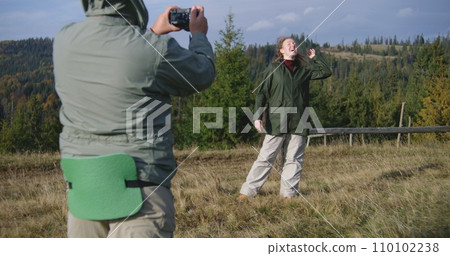 Caucasian man takes photos of woman during hike in mountains 110102238
