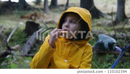 Tourist girl sits in beautiful forest and eats snacks Tourist girl sits in beautiful forest and eats snacks 110102394