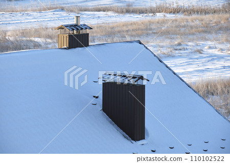 Closeup of house roof top covered with snow in cold winter. Tiled covering of building in wintertime weather Closeup of house roof top covered with snow in cold winter. Tiled covering of building in wintertime weather 110102522