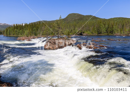 Cascading rapids in Namsskogan under a vibrant blue sky with dense forest edges 110103411
