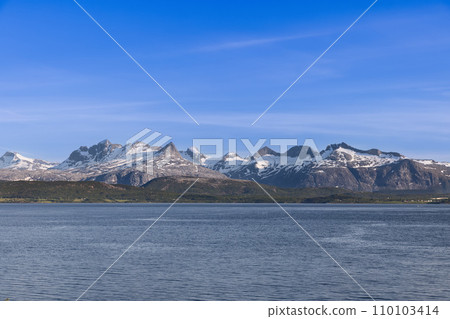 Summer view of snow-capped peaks across Saltfjorden, near Bodo, under a blue sky 110103414