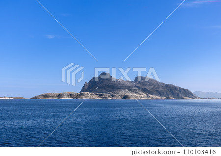 Tranquil view from ferry of a craggy mountain in the North Sea under a luminous sky Tranquil view from ferry of a craggy mountain in the North Sea under a luminous sky 110103416