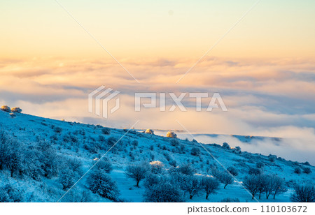 Background photo of low clouds in a mountain valley, vibrant blue and orange sky. Sunrise or sunset view of mountains and peaks peaking through clouds Background photo of low clouds in a mountain valley, vibrant blue and orange sky. Sunrise or sunset view of mountains and peaks peaking through clouds 110103672