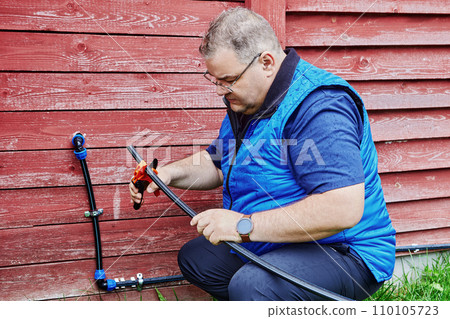 Pipe fitter uses pipe cutter when installing an external domestic water supply in rural area. Pipe fitter uses pipe cutter when installing an external domestic water supply in rural area. 110105723