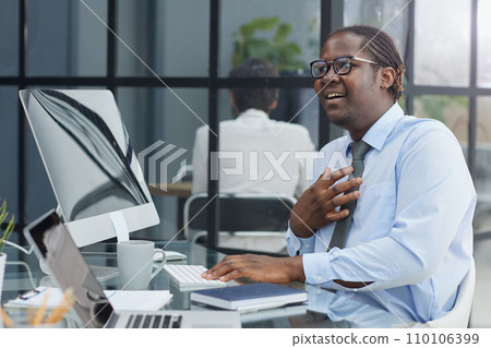a man at a workplace at a table in front of a computer is surprised by the good news 110106399