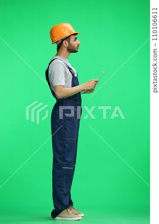 A builder male on a green background thinking. In profile 110106611
