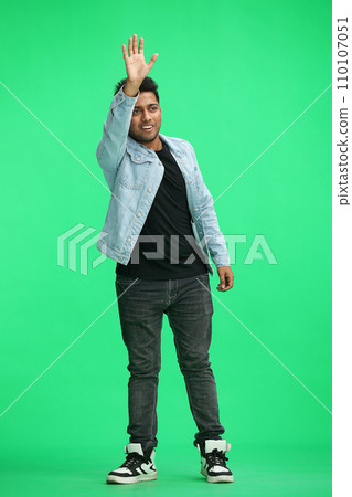a full-length man on a green background waves hello a full-length man on a green background waves hello 110107051