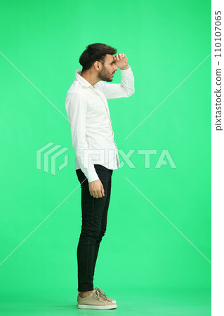 A man on a green background look far. In profile 110107065