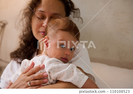 Selective focus on a newborn baby in the hands of a delightful woman, a happy loving mother gently hugging her baby boy. 110108523
