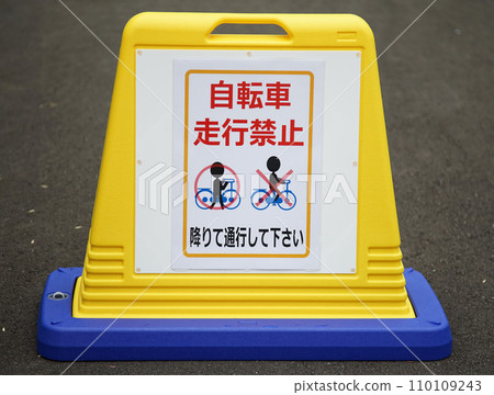 A yellow warning sign on the ground prohibiting bicycle riding 110109243