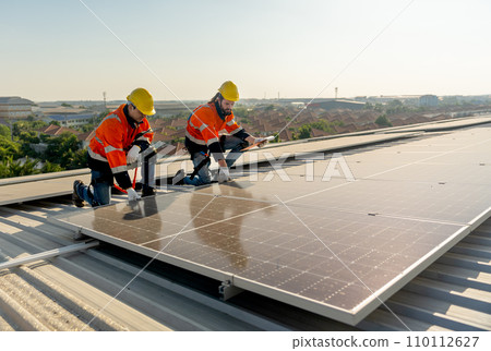 Technician workers hold document pad and tablet check and maintenance the solar panels on rooftop of the building or factory. 110112627