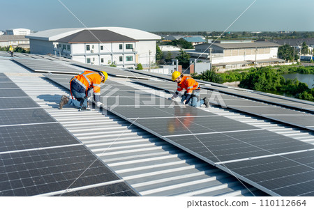 Wide shot of two Caucasian technician workers work with install the solar cell panels on rooftop of factory or the building. Green and sustainable energy concept. Wide shot of two Caucasian technician workers work with install the solar cell panels on rooftop of factory or the building. Green and sustainable energy concept. 110112664