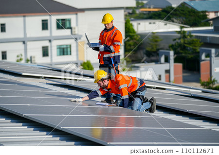 Close up one of technician worker touch to check and maintenance solar cell panels and other co-worker hold laptop to work together on rooftop of factory building. Close up one of technician worker touch to check and maintenance solar cell panels and other co-worker hold laptop to work together on rooftop of factory building. 110112671