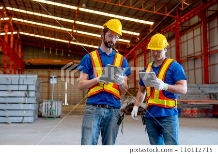 Two Caucasian technician workers hold tablet and stand together to discuss about work in factory workplace area. Good management in the industrial factory concept. Two Caucasian technician workers hold tablet and stand together to discuss about work in factory workplace area. Good management in the industrial factory concept. 110112715