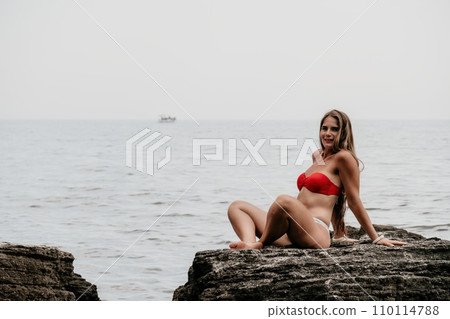 Woman sea yoga. Back view of free calm bliss satisfied woman with long hair standing on top rock with yoga position against of sky by the sea. Healthy lifestyle outdoors in nature, fitness concept. 110114788