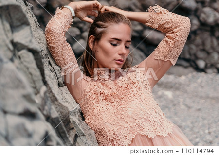 Woman summer travel sea. Happy tourist in beige dress enjoy taking picture outdoors for memories. Woman traveler posing on the beach surrounded by volcanic mountains, sharing travel adventure journey Woman summer travel sea. Happy tourist in beige dress enjoy taking picture outdoors for memories. Woman traveler posing on the beach surrounded by volcanic mountains, sharing travel adventure journey 110114794