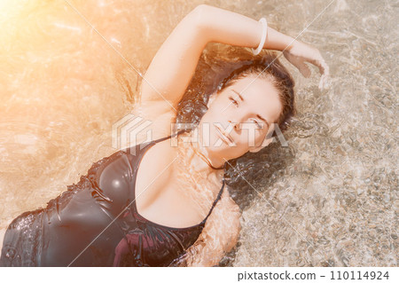Woman summer travel sea. Happy tourist enjoy taking picture outdoors for memories. Woman traveler posing on the beach at sea surrounded by volcanic mountains, sharing travel adventure journey Woman summer travel sea. Happy tourist enjoy taking picture outdoors for memories. Woman traveler posing on the beach at sea surrounded by volcanic mountains, sharing travel adventure journey 110114924