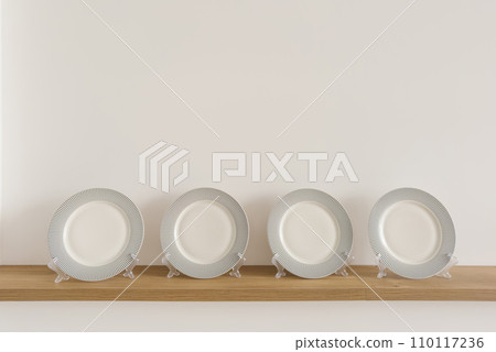 Table plates on stands stand on a wooden shelf in the dining room Table plates on stands stand on a wooden shelf in the dining room 110117236